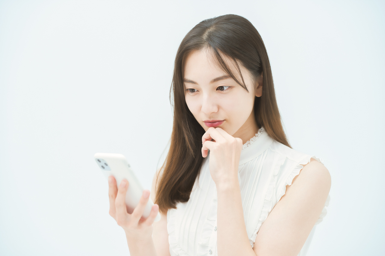 スマホを見ながら悩む女性