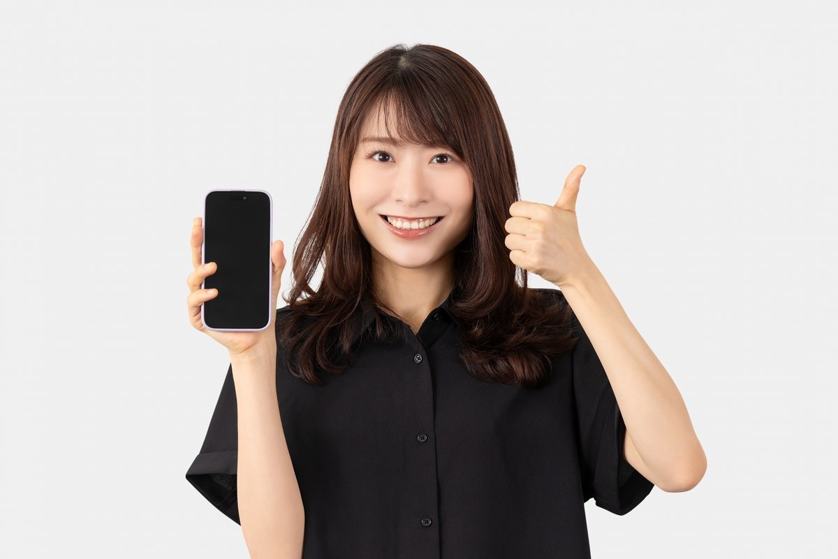 スマートフォンを持ってグッドポーズをしている女性