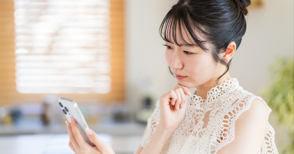 スマートフォンを見て考えている女性